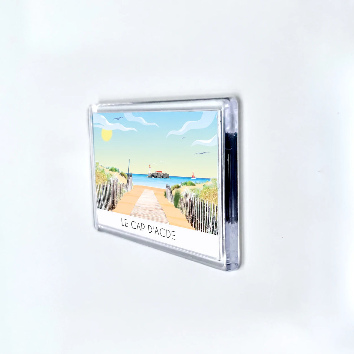 Vue du magnet de profil. Intégration dans un élégant support transparent qui encadre le visuel du Cap d'Agde