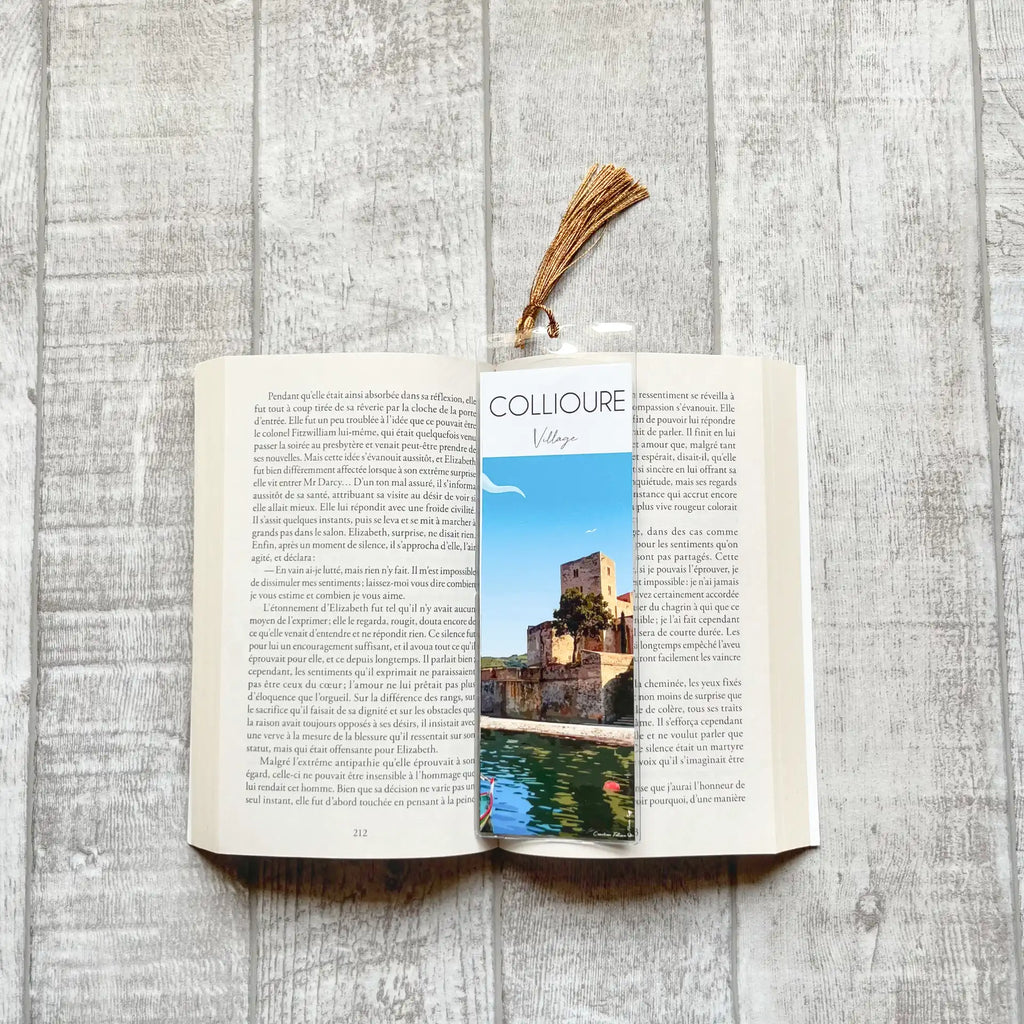 Marque-page Collioure Château Royal posé sur un livre ouvert. illustration originale dessinée à la main par Marie Troff, Foliove. Château Royal de Collioure vu depuis le port, remparts en pierre, barque catalane, pompon doré, Pyrénées-Orientales.